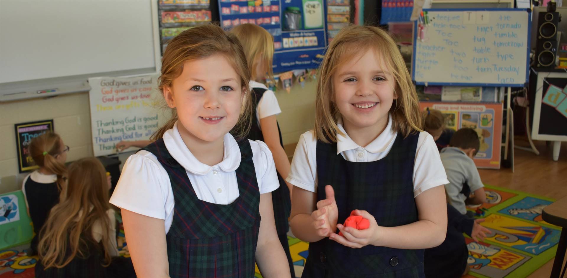 Two elementary school girls, one with a ball of red play dough